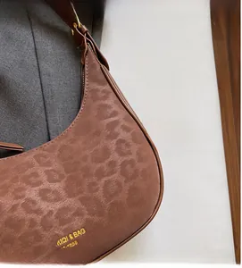 Detailed close-up of brown leopard print hobo bag texture with metallic buckle strap