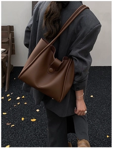 Detail of dark brown pebble leather tote bag with shoulder strap and metal buckle closure