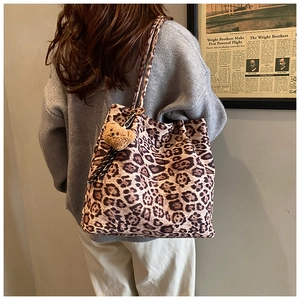 Detail of vintage leopard print tote bag with a brown plush bear charm and long shoulder strap