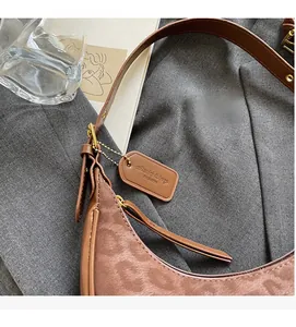 Detail shot of leopard print hobo bag with leather trim on textured background