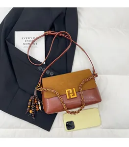 Detail of brown patchwork shoulder bag with gold logo, wooden bead and chain strap