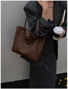 Detail of dark brown pebble leather tote bag with button strap and brand logo