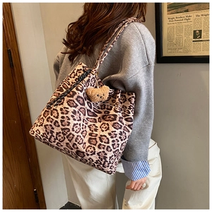 Close-up of leopard print canvas tote bag with woven rope and plush bear charm
