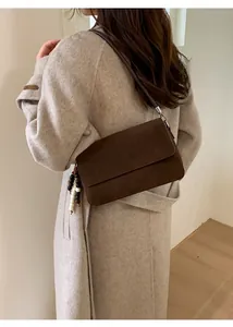 Detail of a dark brown suede baguette bag featuring a chic beaded tassel accessory