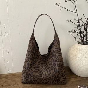 Detailed view of leopard print hobo bag with a dark brown strap on a rustic wooden table