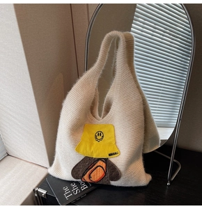 Detailed close-up of cream knit tote bag featuring a cute cartoon embroidery patch