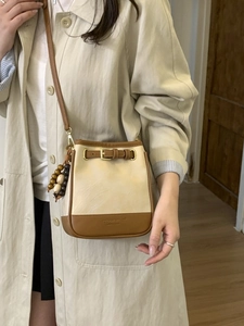 Chic two-tone bucket bag in cream and brown PU leather with a wooden bead charm