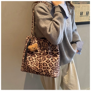 Detail of leopard print tote bag with plush bear charm worn over the shoulder