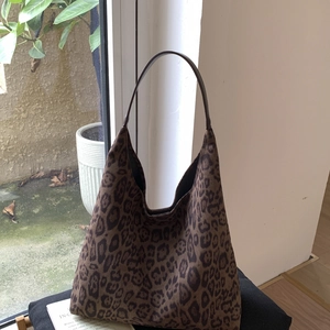 Detailed view of large leopard print tote bag on dark fabric with natural light background