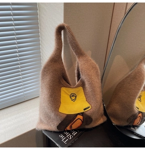 Detail of soft brown faux fur tote bag with yellow bucket hat embroidery and orange pocket