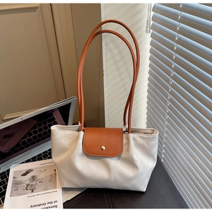 Minimalist white leather tote bag detail with brown handles in an office setting