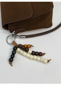 Detail of beaded bag charm with multi-color wooden beads on suede shoulder bag