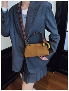 Detail of brown suede pillow bag with large gold ring hardware and leather strap