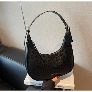 Detail of hobo crescent bag with dark leopard print texture and gold logo text on the side