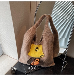 Detailed close-up of brown plush tote bag featuring yellow smiley face and backpack patches
