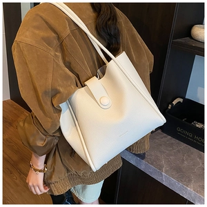 Detail of white lychee grain leather tote bag with brand logo and slim shoulder strap