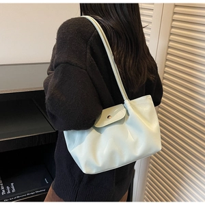 Detailed back view of a mint green pleated faux leather tote bag worn as a shoulder bag