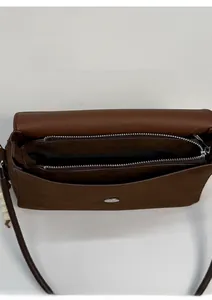 Detail view of brown faux suede crossbody bag with dual zipper compartments and magnetic buckle