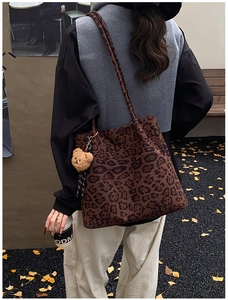 Close-up of leopard print tote bag with bear charm on a scenic autumn street