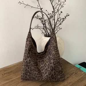 Macro detail of leopard print tote bag texture and brown leather strap on wooden stool