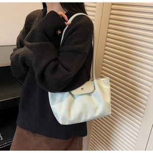Detail of mint green leather tote bag with round metal buckle and soft pleated texture