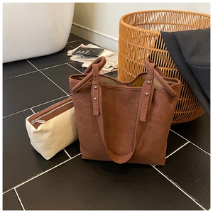 Detail der matten braunen Shopper-Tasche mit Nieten und cremefarbener Innentasche