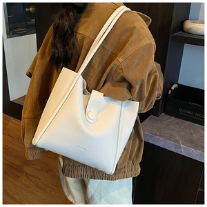 Detailed view of white litchi pattern leather tote bag with brand logo shown on model