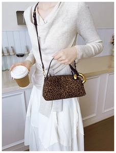 Detailed view of leopard print handbag featuring unique gold U-shaped metal handles