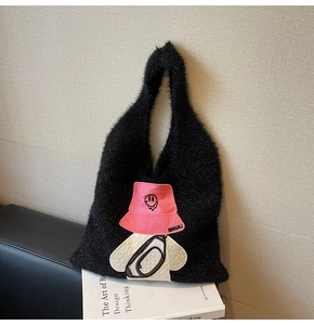 Detail of black faux fur tote bag with pink fisherman hat embroidery and soft texture
