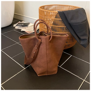 Detailaufnahme der braunen Shopper-Tasche aus Wildleder mit runden Griffen und Gurt