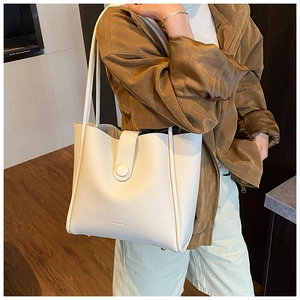 Detail of off-white lychee grain leather tote bag with MOCOMO logo and buckle strap