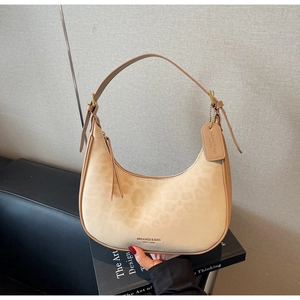Detail shot of a beige leopard print crescent bag with suede texture and leather strap