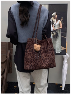 Close-up of vintage leopard print tote bag with brown bear keychain on a shoulder strap