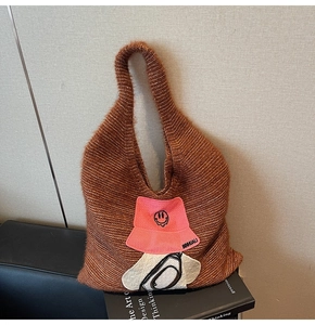 Detail of plush knit tote bag featuring a pink hat pattern and smiley face embroidery