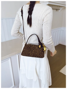 Detailed view of leopard print satchel with leather handles and gold metal hardware