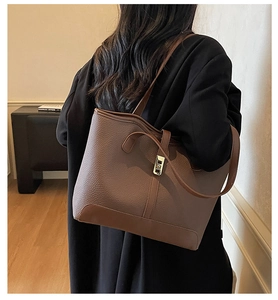 Macro detail of dark brown leather tote bag with elegant lychee pattern and gold lock