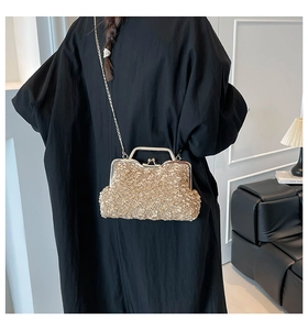 Détail d'une pochette de soirée dorée à texture gravillonnée avec fermoir métallique
