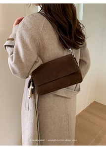 Detail of dark brown suede shoulder bag with beaded fringe tassel and minimalist flap cover