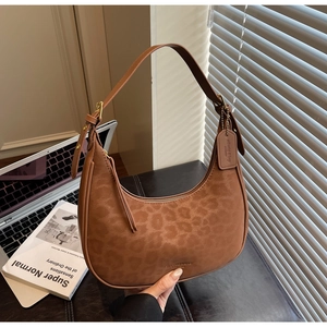 Detailed view of brown leopard embossed leather texture and gold hardware on a hobo bag