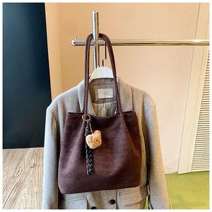 Detail of dark brown large tote bag with a cute teddy bear charm on a grey blazer