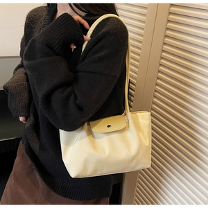 Close-up of cream-colored shoulder tote bag with magnetic flap and soft pleated texture