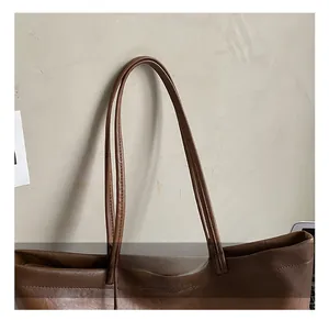 Detail view of smooth brown leather tote straps and fine stitching on the bag