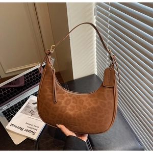 Detail shot of leopard print textured crescent bag with adjustable strap in office setting