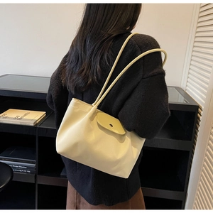Detail view of cream beige leather tote bag featuring slim shoulder straps and magnetic clasp