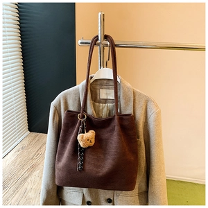 Deep brown tote bag detail with plush bear charm and striped ribbon on a blazer jacket