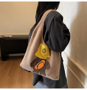 Detail showing the brown knitted tote bag texture and cute cartoon patch with fisherman hat