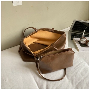 Detail view of dark brown tote bag with yellow suede lining and matching zipper pouch