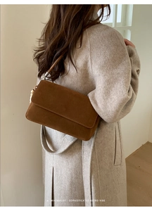 Brown suede flap handbag detail shown on a beige wool coat for a chic winter commute style