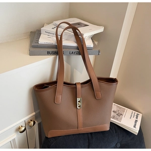 Détail d'un grand sac cabas marron foncé en cuir grainé avec boucle dorée élégante