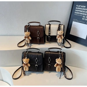 Detail of vintage crossbody bags with double buckles and cute bear plush charms
